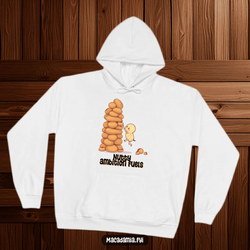 Funny hoodie featuring a macadamia nut character attempting to climb a giant, wobbly stack of macadamia nuts, perfect for cozy reflection.